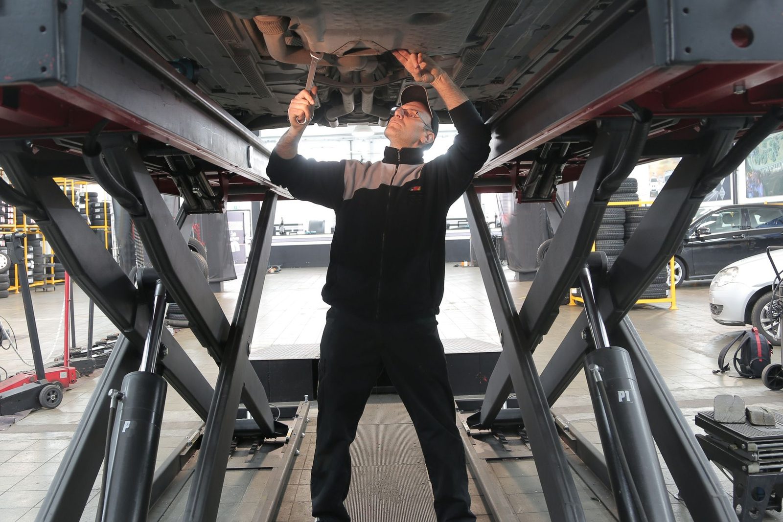 Technician working under a car raised on a lift